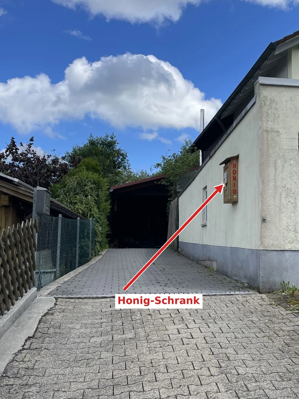 Zufahrt mit Pfeil zum Honig-Selbstbedienungsschrank an der Garagenwand